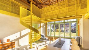 Un interior moderno con una escalera en espiral, ventanas amplias y un comedor.