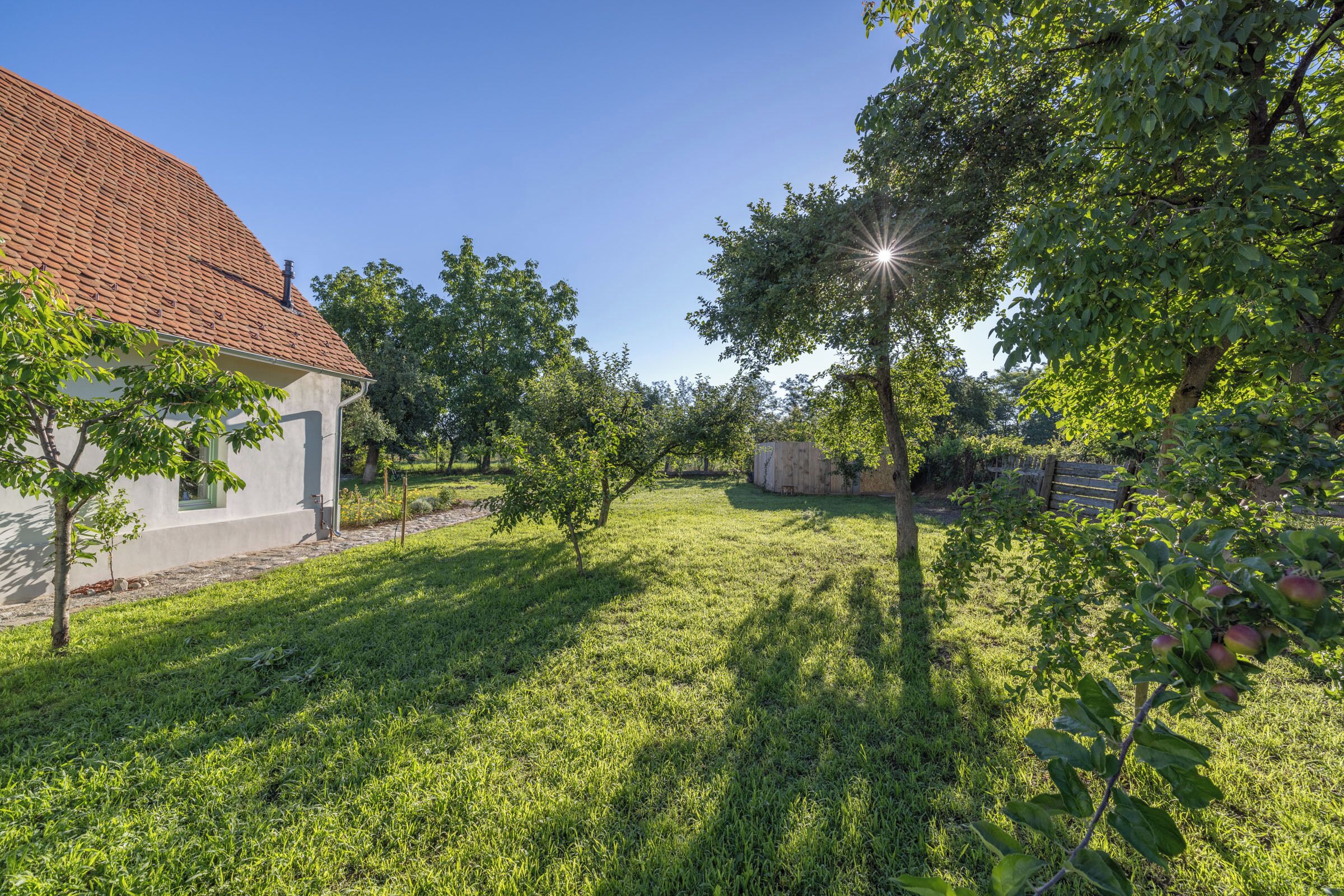 A house with a red-tiled roof, surrounded by a well-maintained lawn and trees.
