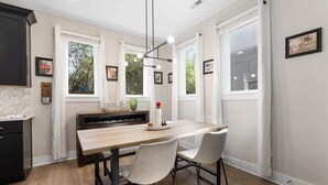 Una cocina moderna con una mesa de madera, dos sillas y una estantería para vinos.