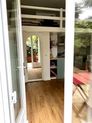 Une pièce compacte à plusieurs niveaux, dotée d’un plancher en bois, d’un bureau intégré et d’un petit coin salon.