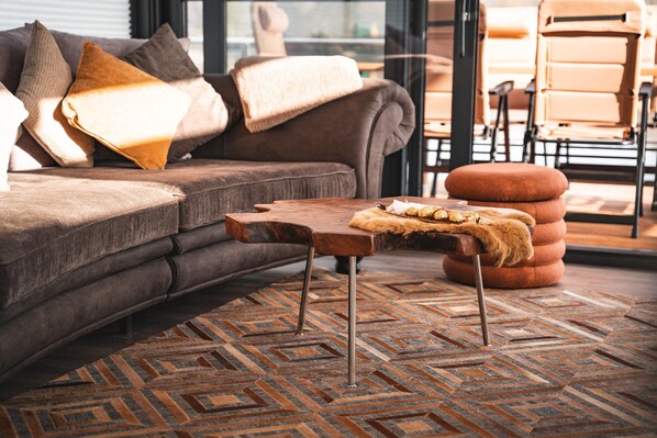 Un salon moderne avec un canapé marron, une table basse en bois et un tapis à motifs.