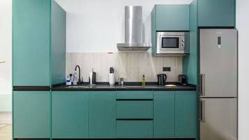Una cocina moderna con armarios color turquesa, una campana de acero inoxidable, un microondas y un refrigerador.