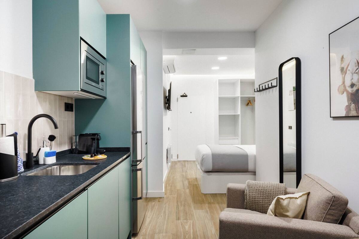 A compact living space with a kitchenette, a bed, and a seating area.