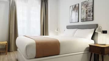 A modern hotel room with a large bed, a bedside table with a lamp, and two framed pictures on the wall.