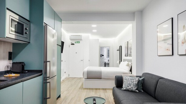 A modern hotel room with a kitchenette, a bed, a sofa, and a small table. - Limehome Madrid Calle de Matilde Diez (Madrid)
