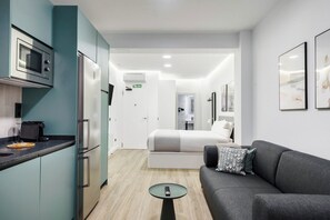 A modern hotel room with a kitchenette, a bed, a sofa, and a small table. - Limehome Madrid Calle de Matilde Diez (Madrid)