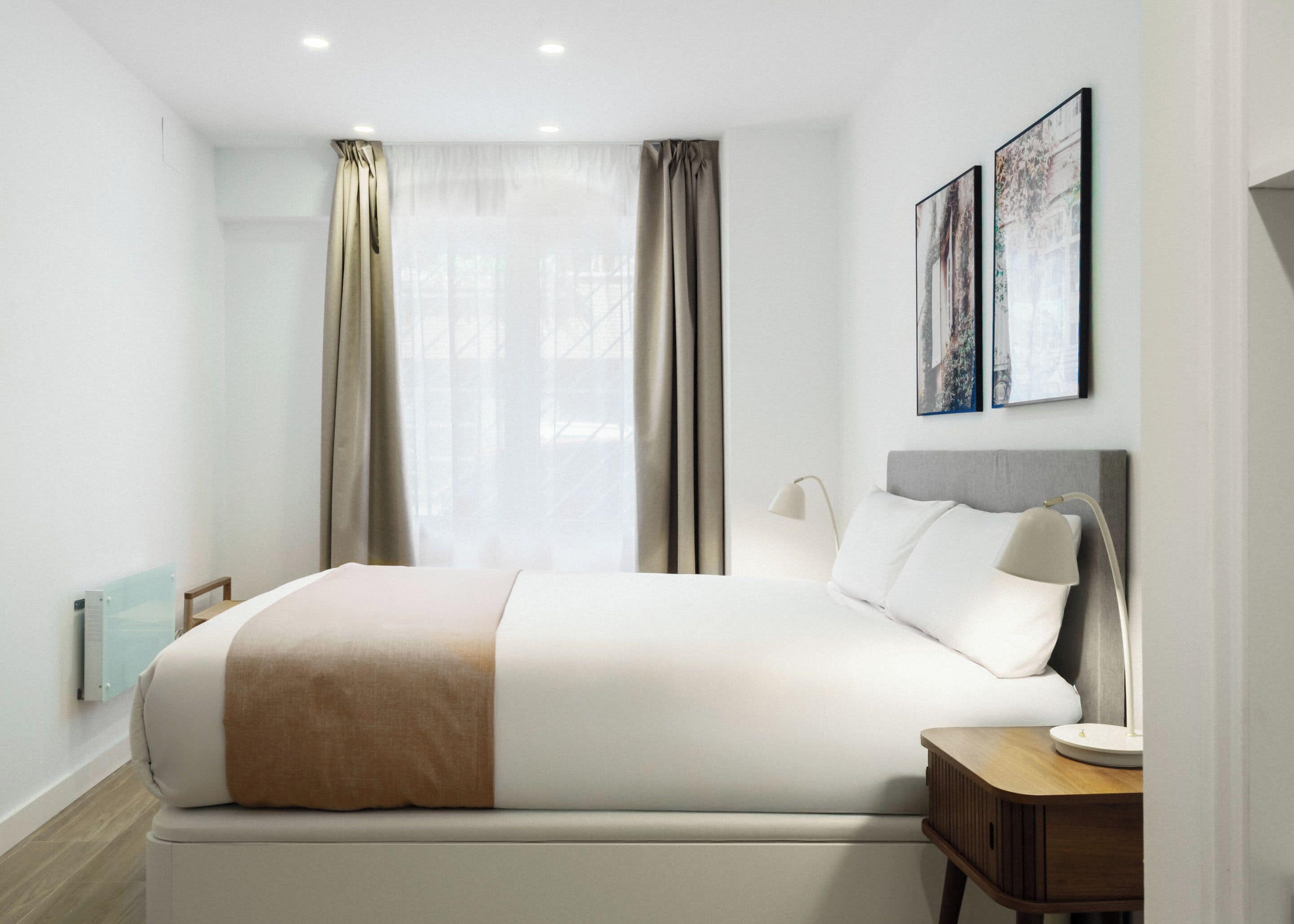 Une chambre d’hôtel moderne avec un grand lit, une table de chevet et une fenêtre avec des rideaux.