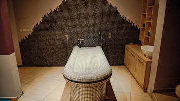 Bathroom features a unique mosaic tile wall and a round bathtub.