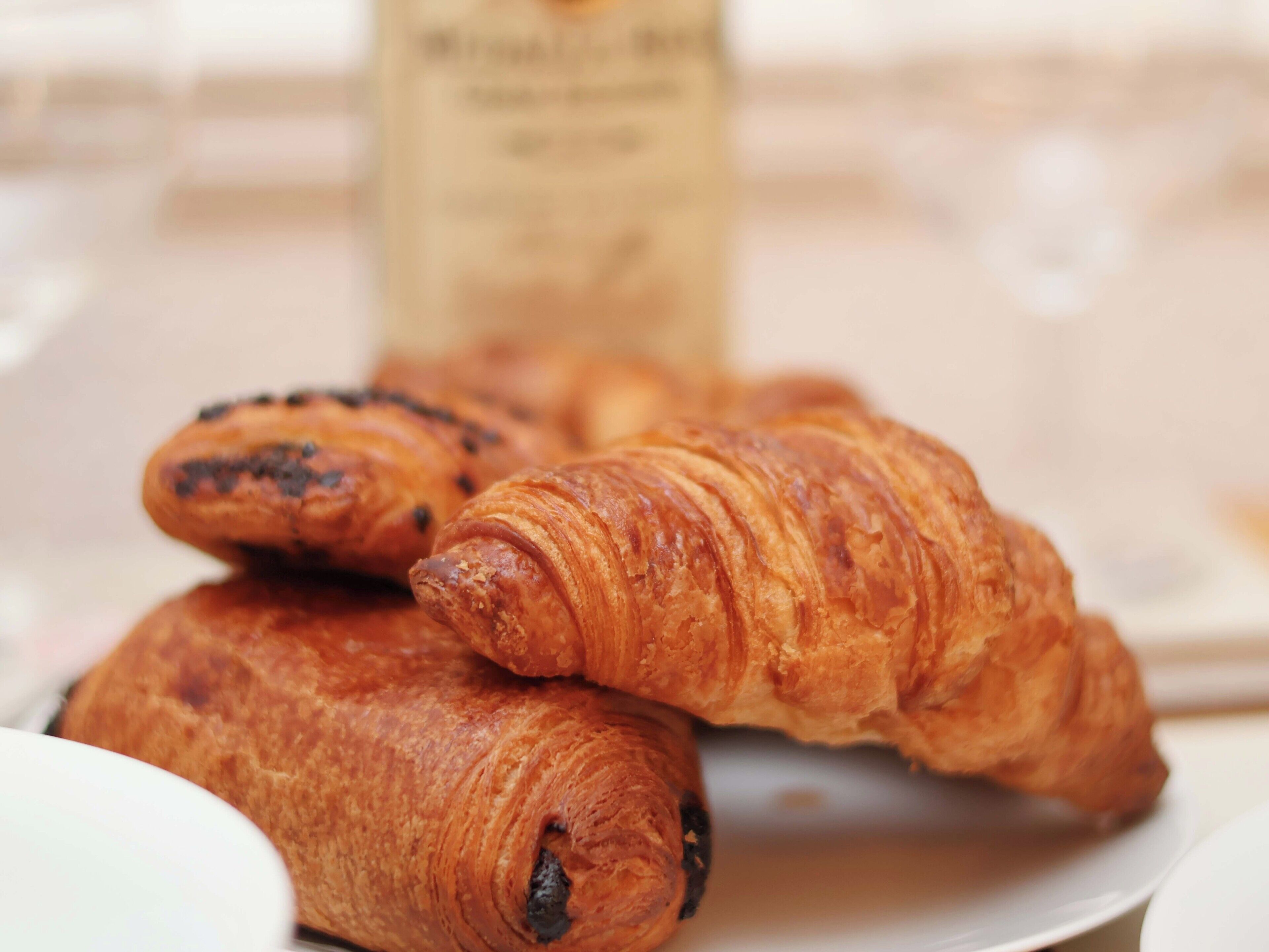 Um prato com croissants e uma garrafa de café.