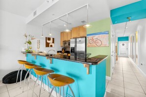 Una cocina moderna con una isla central, taburetes de bar y un refrigerador grande.