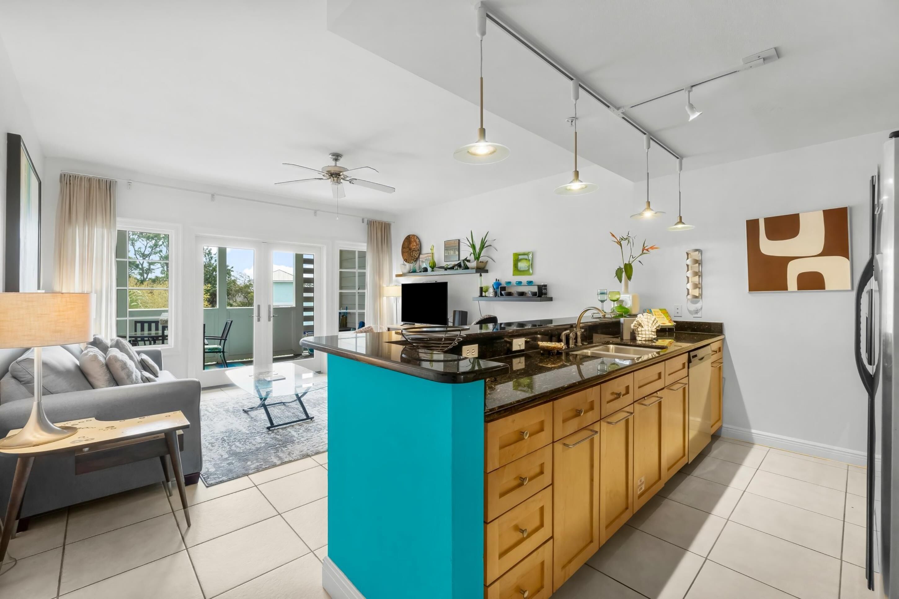 Una cocina moderna con una isla central, armarios de madera e iluminación colgante.