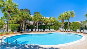 Una piscina con sillas de descanso y palmeras.