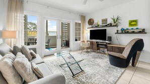 A modern living room with a sofa, TV, and a ceiling fan. - Cassine Station by Panhandle Getaways (Santa Rosa Beach)