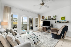 A modern living room with a sofa, TV, and a ceiling fan. - Cassine Station by Panhandle Getaways (Santa Rosa Beach)