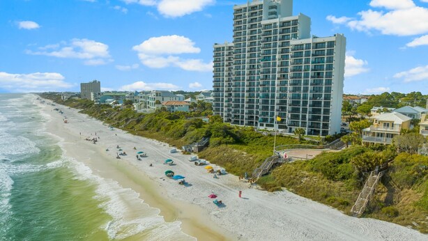 Un hotel frente a la playa con una playa arenosa, vistas al océano y una construcción de estilo moderno.