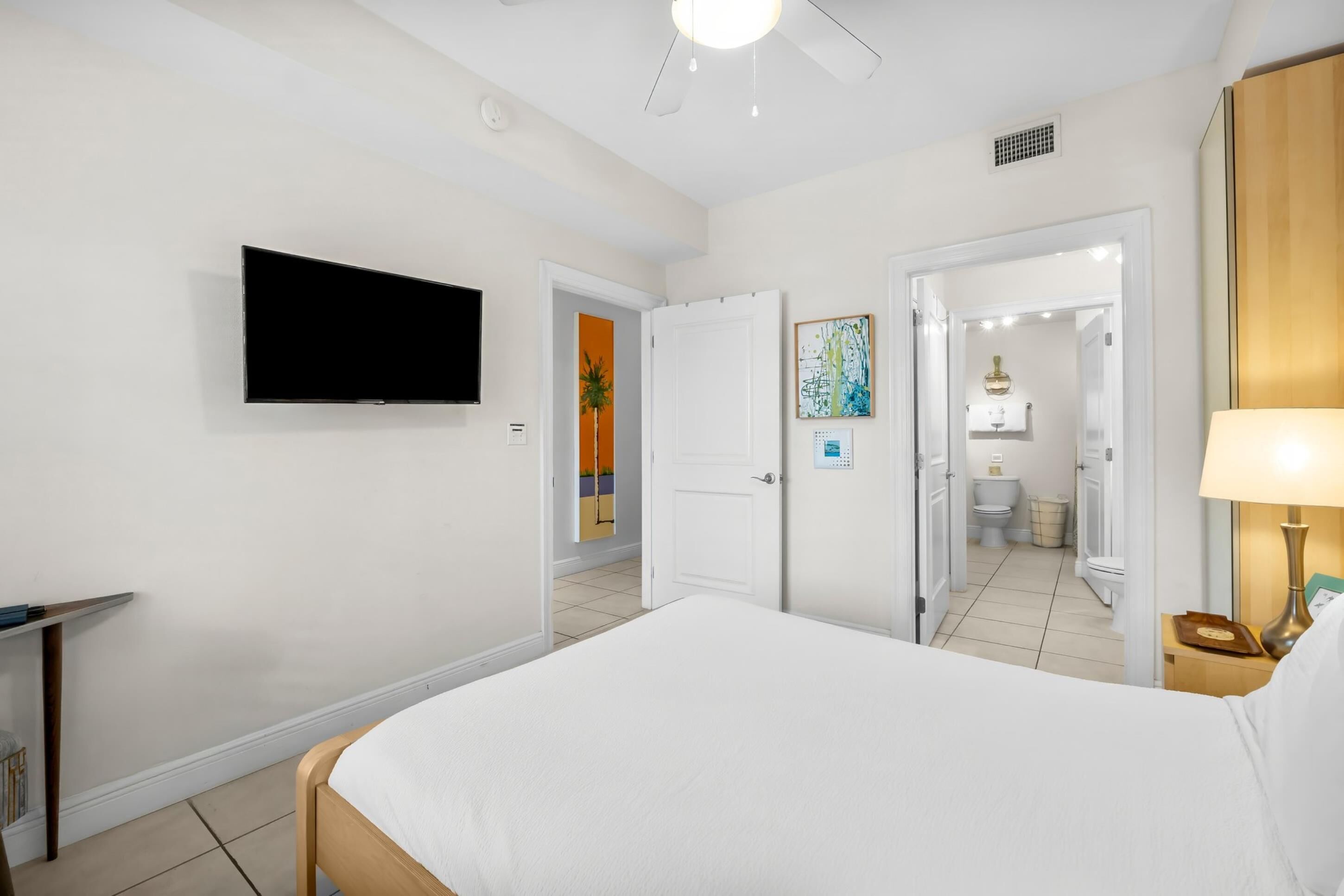 Ein Hotelzimmer mit Bett, Fernseher, Schreibtisch und einem durchgegangenen Tür sichtbaren Badezimmer.