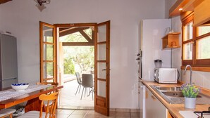 A kitchen with a dining area, wooden cabinets, a microwave, and a sink. - Sardinia Re - Villa Green Val (Alghero)