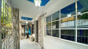 A corridor with a statue, a window with metal bars, and a ceiling light. - Casa Turística los Doce Apostoles  (Cartagena)
