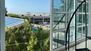 A view from a window overlooking a building with a blue roof and a staircase leading to a balcony. - Casa Turística los Doce Apostoles  (Cartagena)