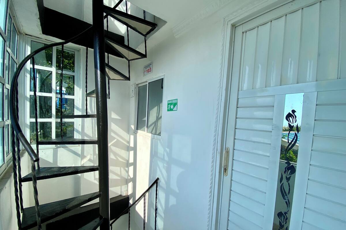 A spiral staircase leading to a door with a green sign indicating a gender-neutral restroom.