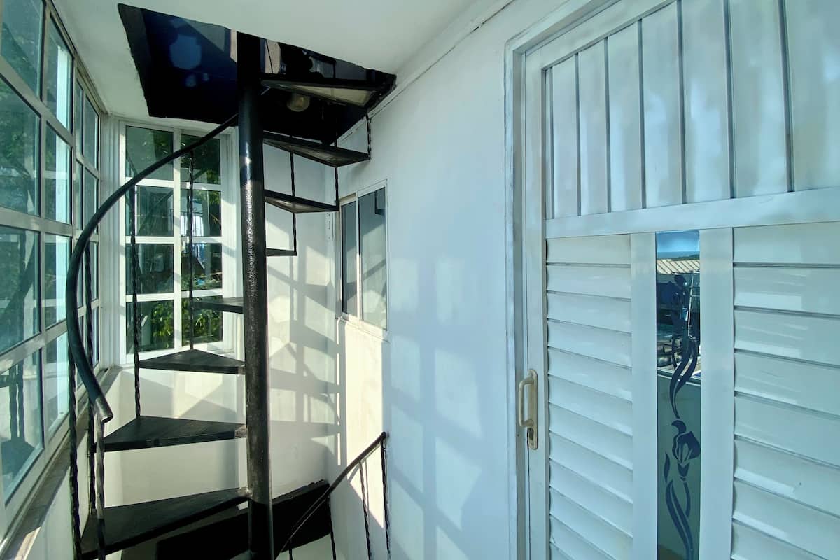 A room with a spiral staircase, large windows, and a door with horizontal blinds.