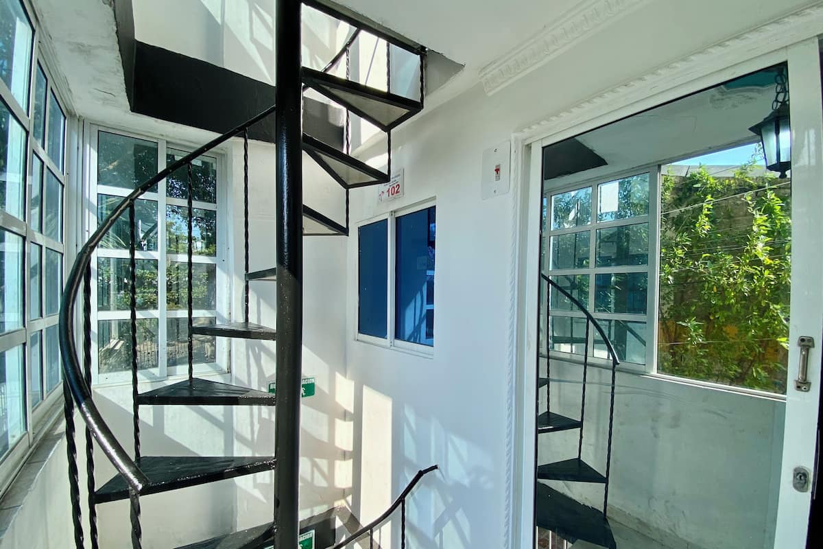 A spiral staircase with a metal railing, leading to a balcony with a glass door.
