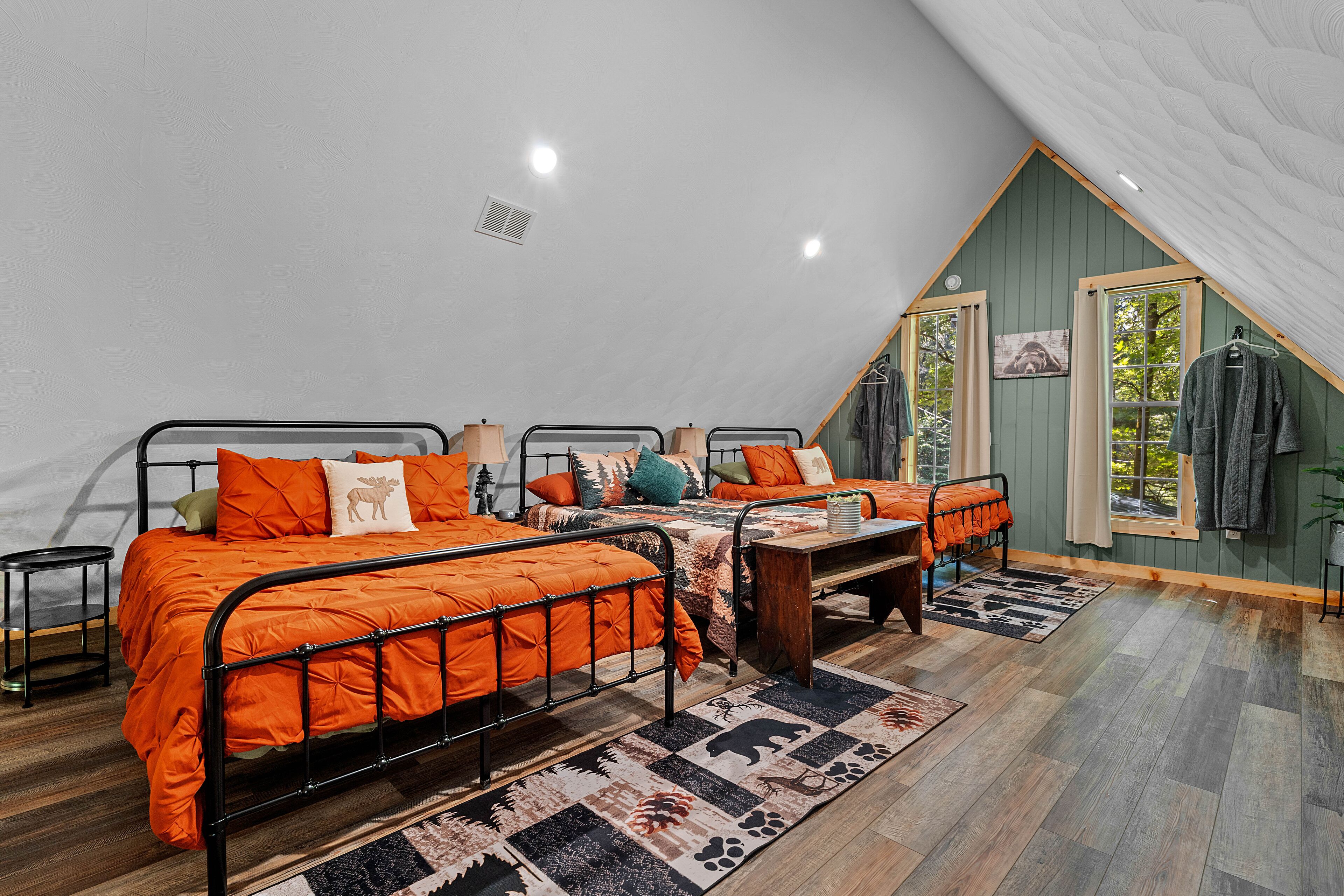 A bedroom with two beds, a wooden floor, and a sloped ceiling.