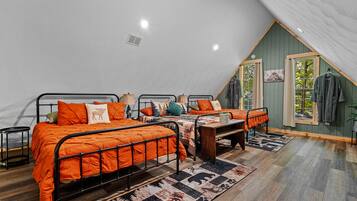 A bedroom with two beds, a wooden floor, and a sloped ceiling.