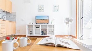 Una cocina moderna con armarios de madera, una encimera blanca, un televisor y un ventilador.