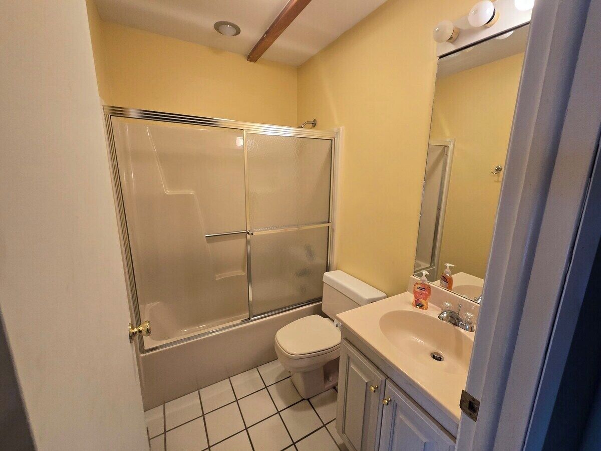 Een badkamer met een douche met glazen wand, een toilet en een wastafel met spiegel.