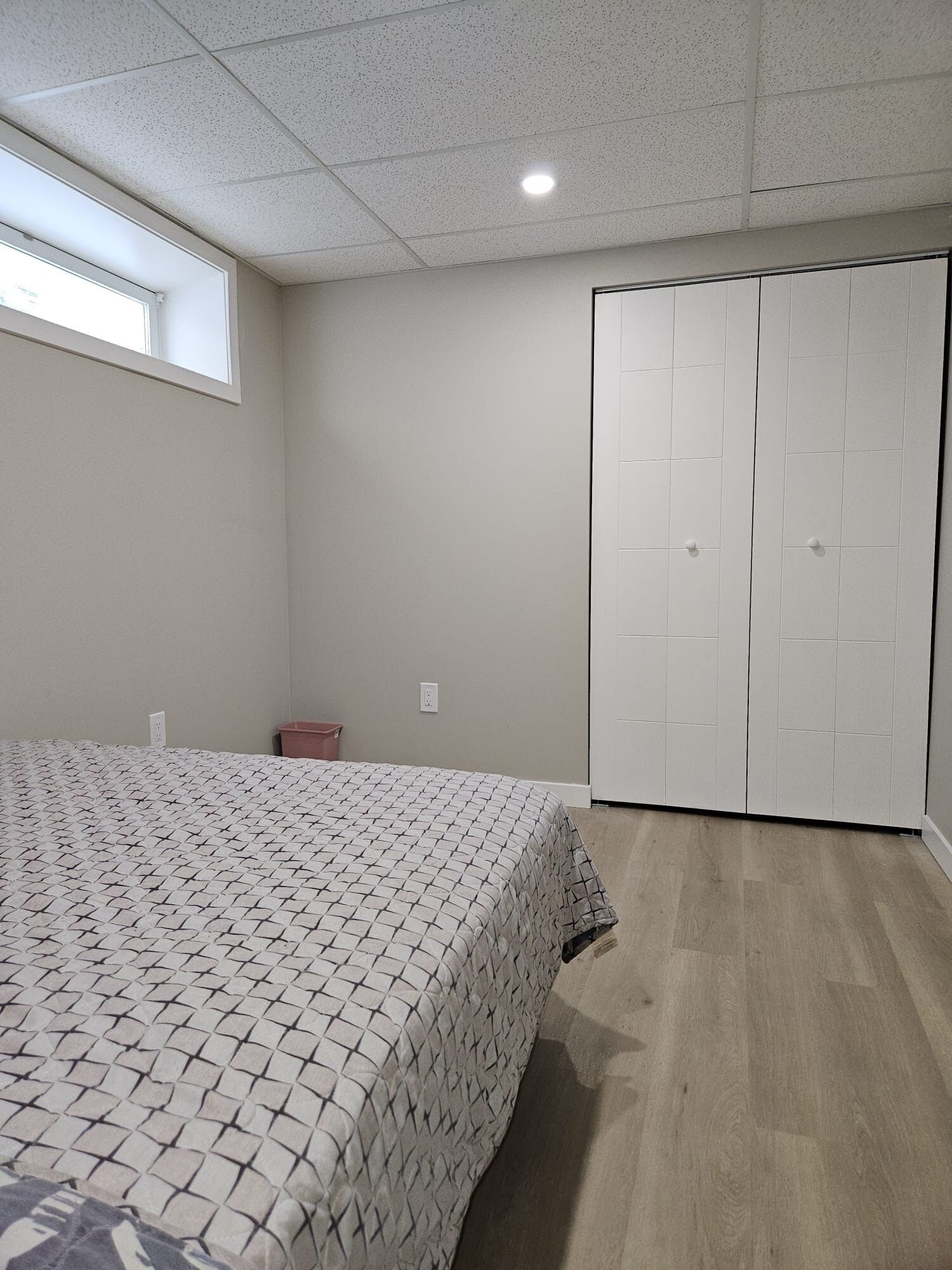 A bedroom with a bed, a closet, and a window.