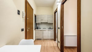 A compact kitchen with wooden cabinets, a white countertop, and a built-in refrigerator. - Emilia Studios 1 (Modena)