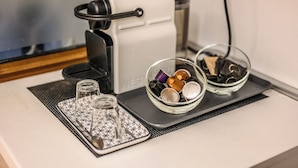 A coffee maker, two glass bowls with various items, and a tray with a spoon and glass on a table. - Emilia Studios 1 (Modena)