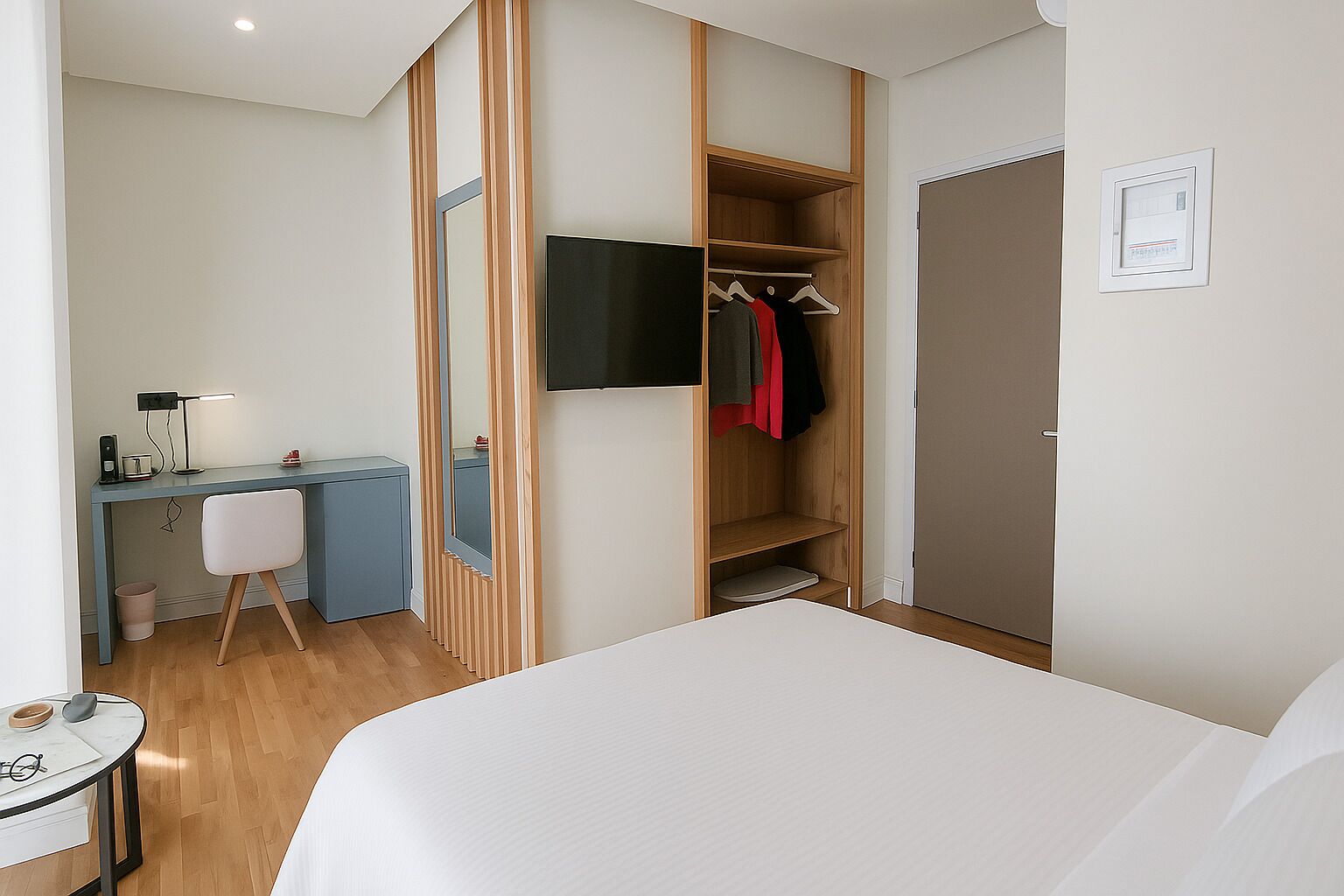 Una habitación de hotel con cama, escritorio, silla, armario y televisor.