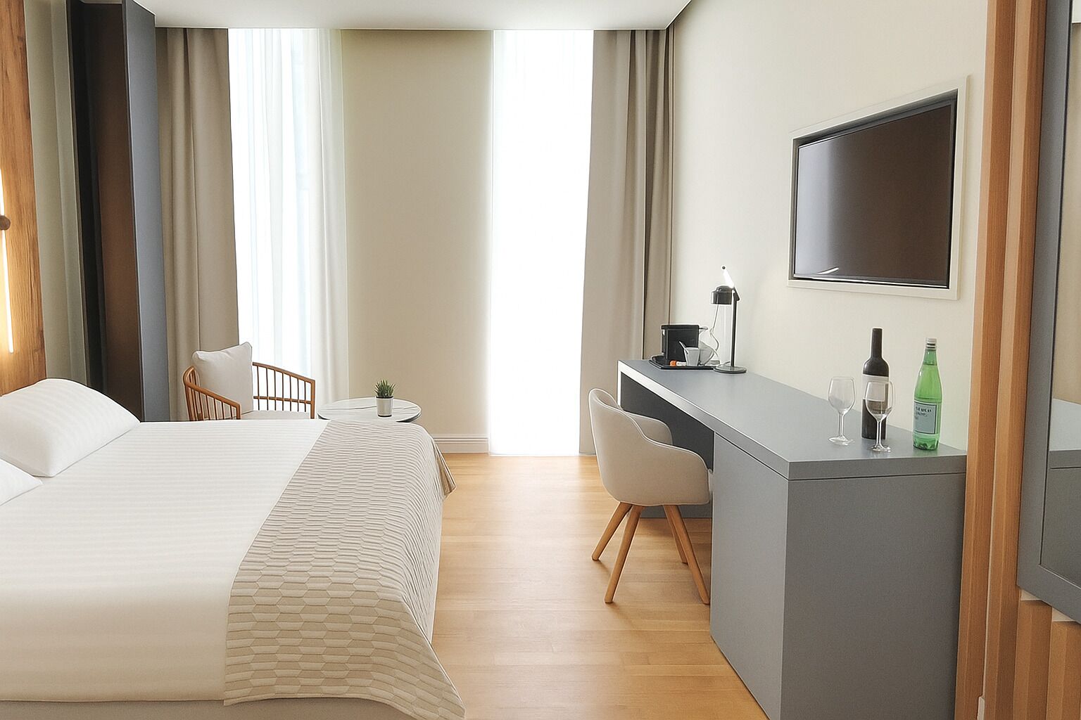Hotelkamer met een bed, een bureau, een stoel, een televisie en een kleine tafel met een plant en een fles.