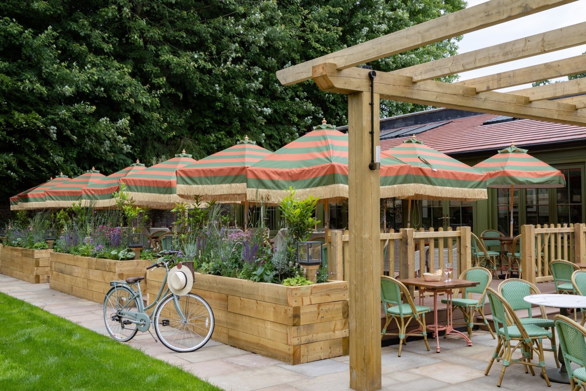 A patio area with wooden planters, striped umbrellas, and wicker chairs.