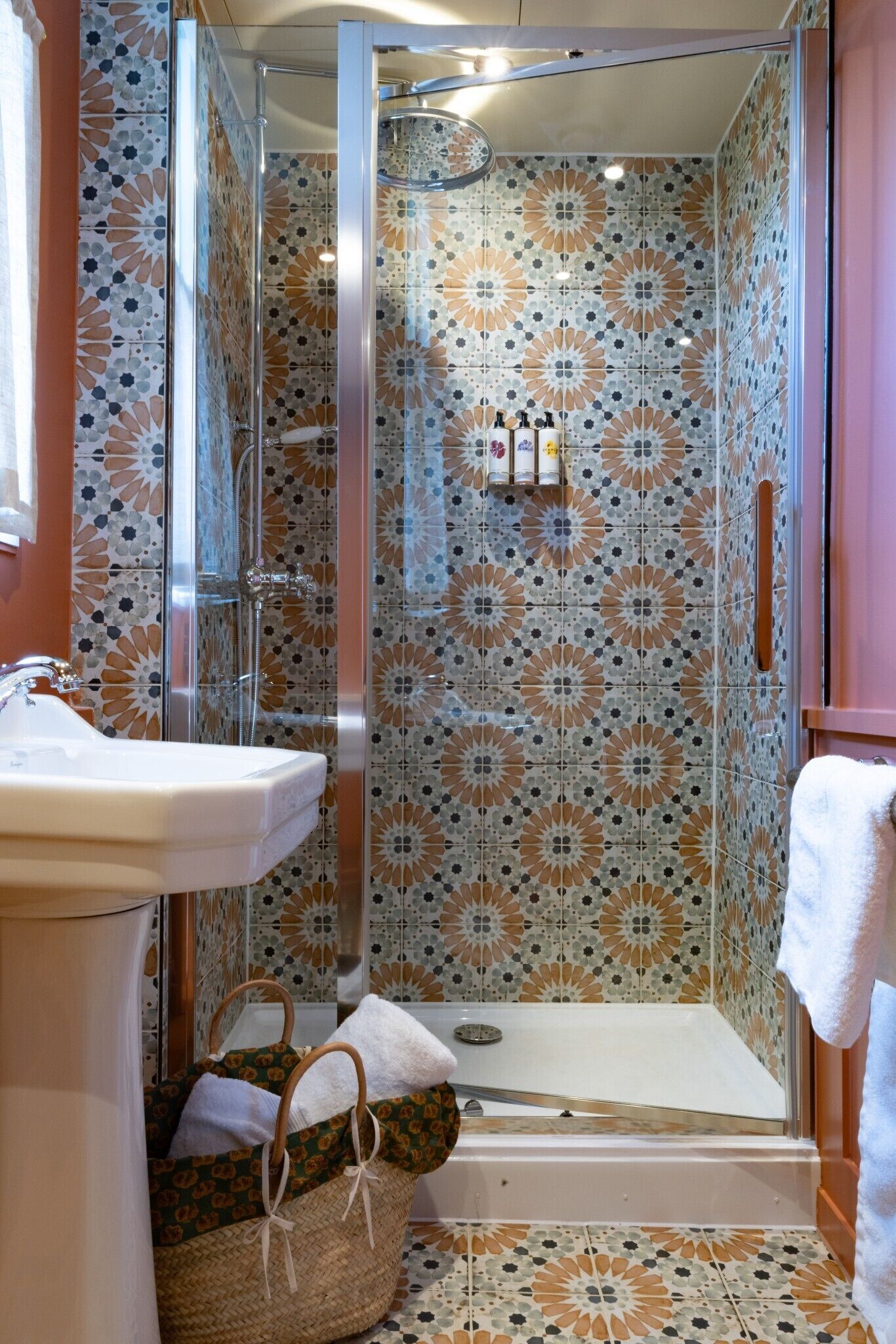 Een badkamer met een douche, een wastafel en een betegelde muur met een patroon.