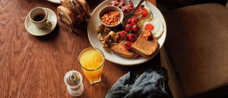 A breakfast setting with toast, eggs, beans, and a glass of orange juice on a wooden table.