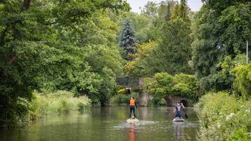 A person paddleboarding on a calm river surrounded by lush greenery.