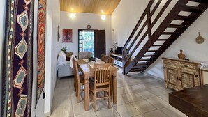 A spacious dining area with a wooden table and chairs, a staircase, and a decorative wall hanging. - Refuge Brisa do Campo | IG - SOLAR DO CAMPO (Rio de Janeiro)