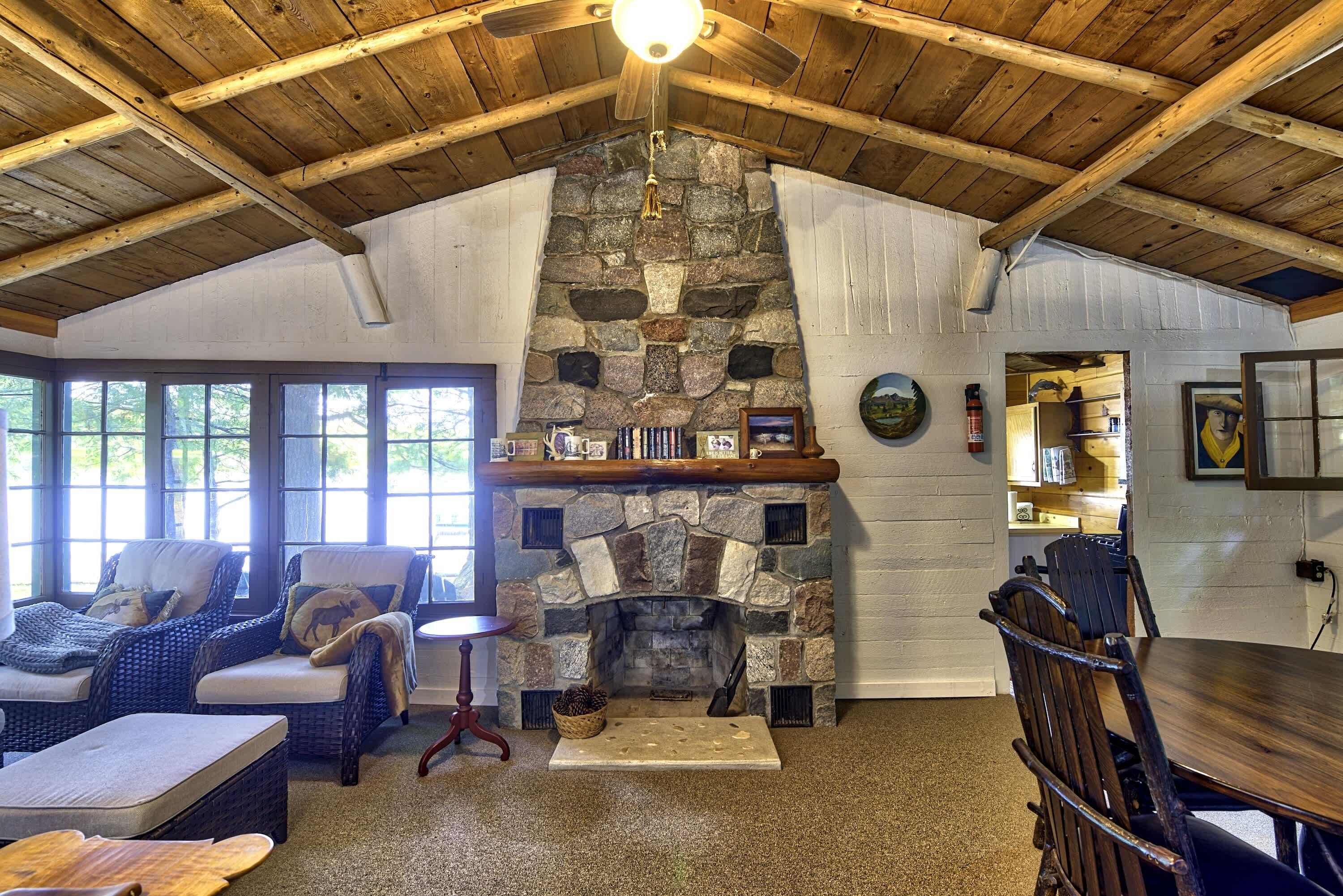 Un interior acogedor con chimenea de piedra, muebles de mimbre y techo de madera.
