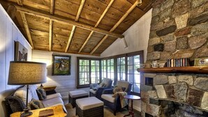 A cozy room with a stone fireplace, a sofa, a chair, a table with a lamp, and a painting on the wall.