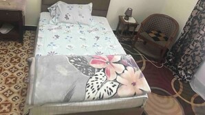 A bed with floral bedding, a bedside table with a lamp, a chair, and a patterned rug. - Vacation room (El Biar)
