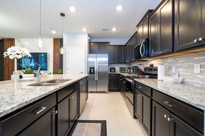 Equipped with a double sink, refrigerator, microwave, and coffee maker, this kitchen offers ample space for meal preparation.