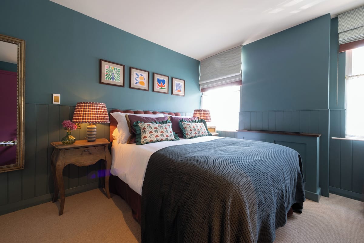 A bedroom with a bed, nightstands, a dresser, and framed artwork on the wall.