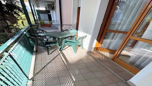A small balcony with a table and chairs, a tiled floor, and a view of the outside. - Great Flat in a Residence With Pool in Rosolina (Rosolina)