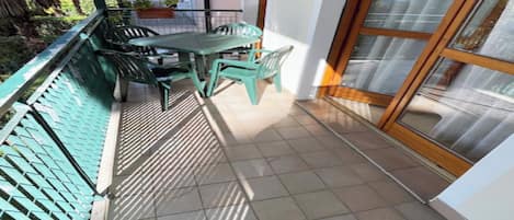 A small balcony with a table and chairs, a tiled floor, and a view of the outside.