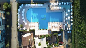 An aerial view of a hotel with a swimming pool surrounded by sun loungers and umbrellas, a parking area, and greenery. - Great Flat in a Residence With Pool in Rosolina (Rosolina)
