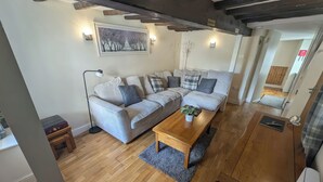 A modern living room with a sectional sofa, a wooden coffee table, and a painting on the wall. - Hocking Cottage (Torquay)