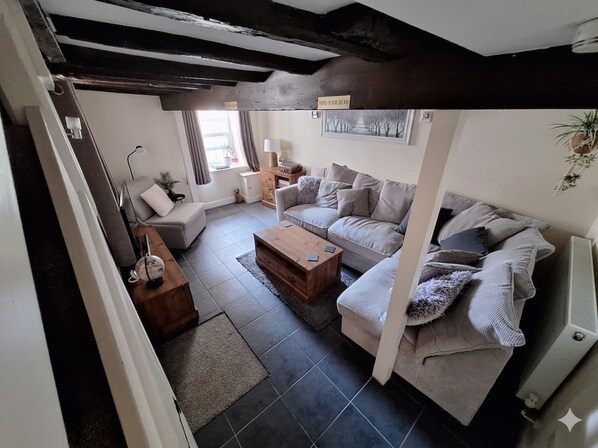 A living room with a sofa, a coffee table, and a lamp. - Hocking Cottage (Torquay)